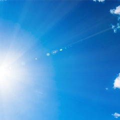 Photo of a bright blue sky with clouds and rays of sun