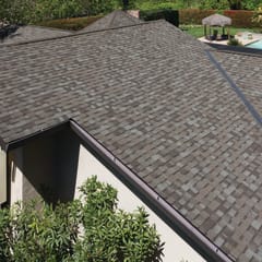 Photo of the top of a roof with COOL shingles installed, with green grass and a pool in the background