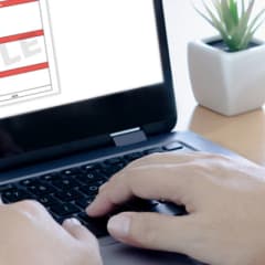 Closeup photo of hands typing on a laptop with a sample roof quote on the screen