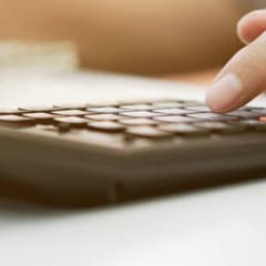Closeup of a person's hand on a desk using a calculator