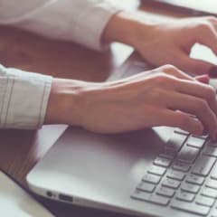 Photo of hands typing on a laptop keyboard
