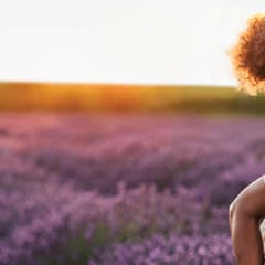 Woman holding child on her back in a field of lavender