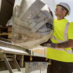 a plant worker is unloading stone wool from a truck to be used in the Rewool program
