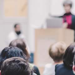 cilvēki klausās PAROC rīkotajā konferencē.