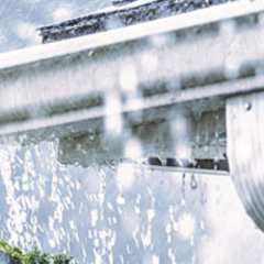 Regnvatten droppar ned från hängrännan på huset.