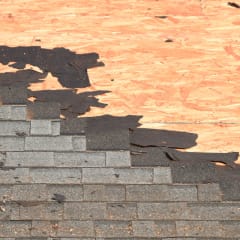 Closeup photo of a roof with old shingles being torn off