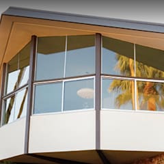 Mid-century modern home in Palm Springs, California featuring dramatic angular rooflines, cantilevered design, large glass windows, and stone exterior walls surrounded by palm trees and desert landscaping.