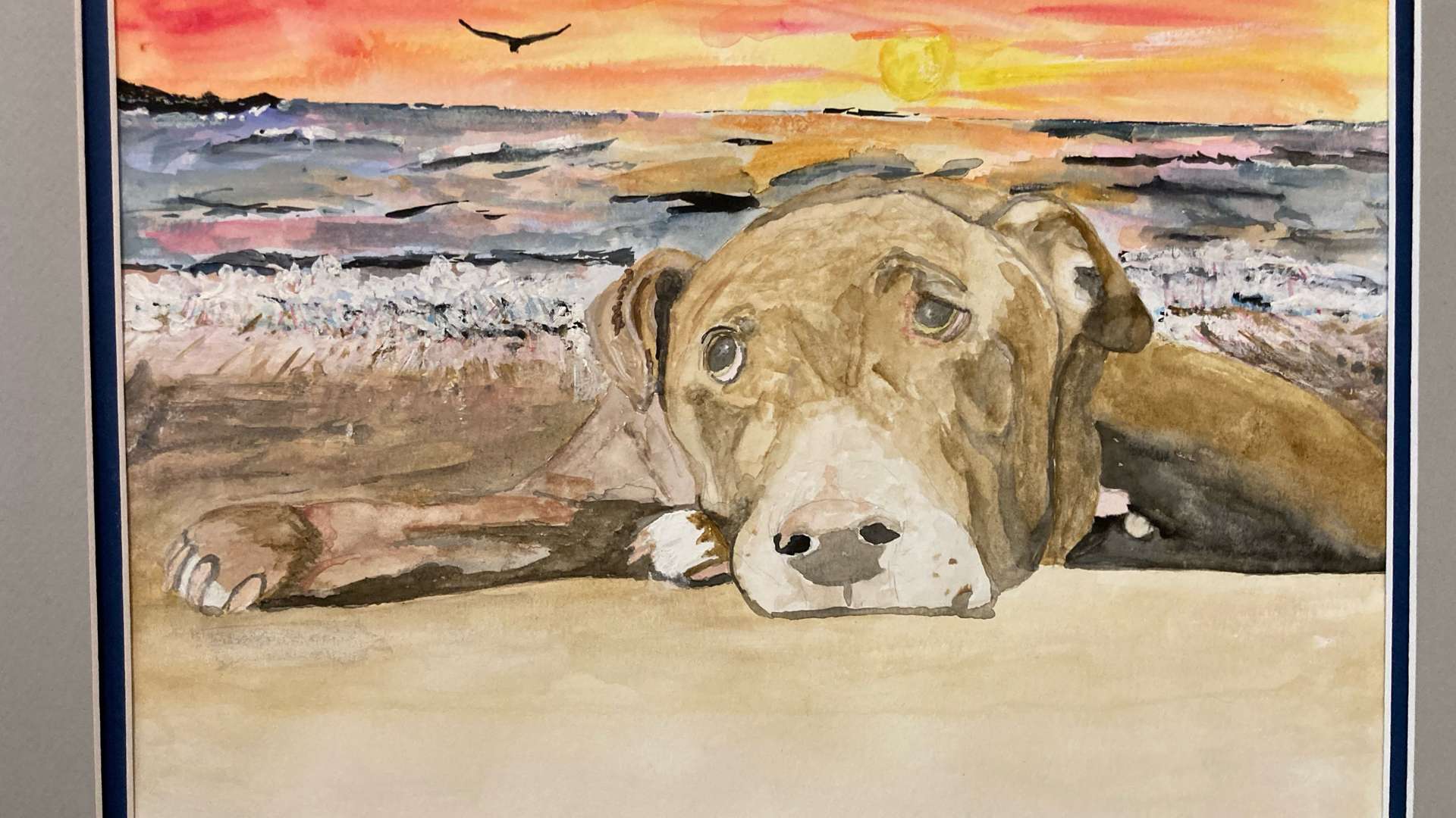   Watercolor painting of a brown dog lying on a beach with ocean waves and a vibrant sunset in the background.