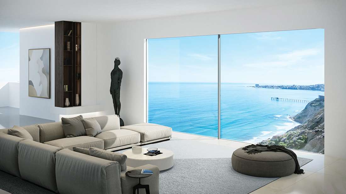 Modern living room with panoramic ocean view, large sectional sofa, minimalist decor, and floor-to-ceiling glass windows overlooking coastal landscape.