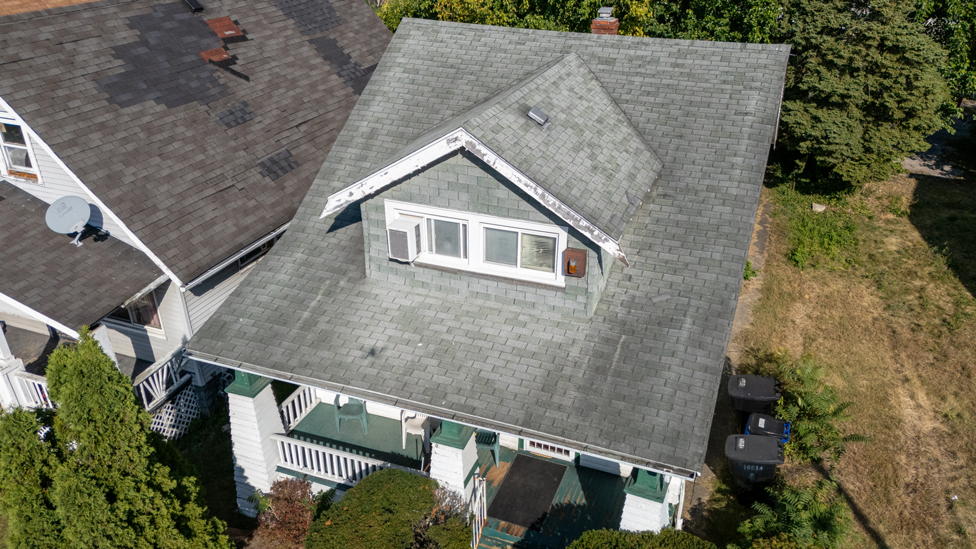 White home with grey 3tab shingles with moderate visual damage.
