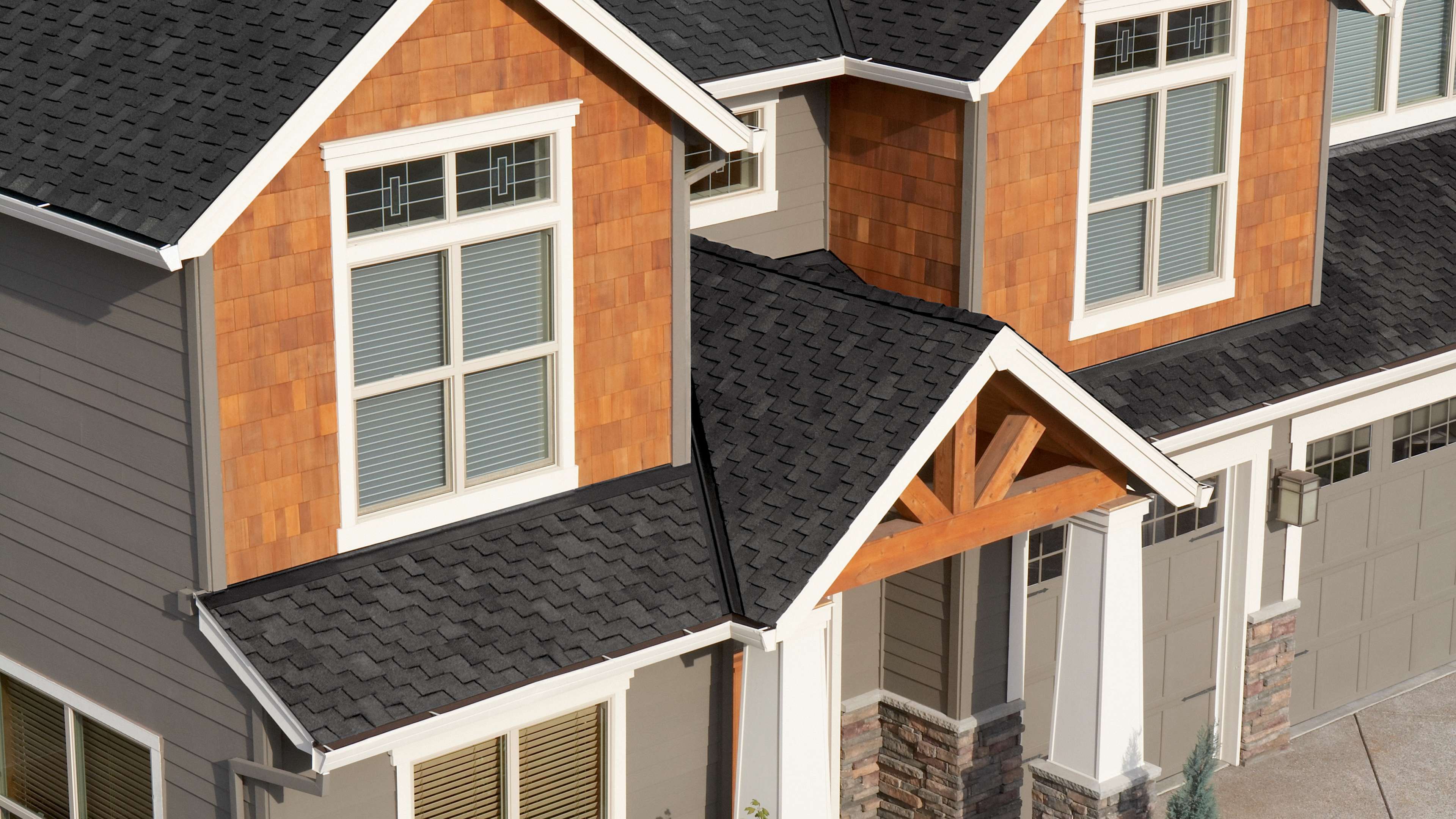 Two-story home with tan siding and Woodcrest® Carbon shingles