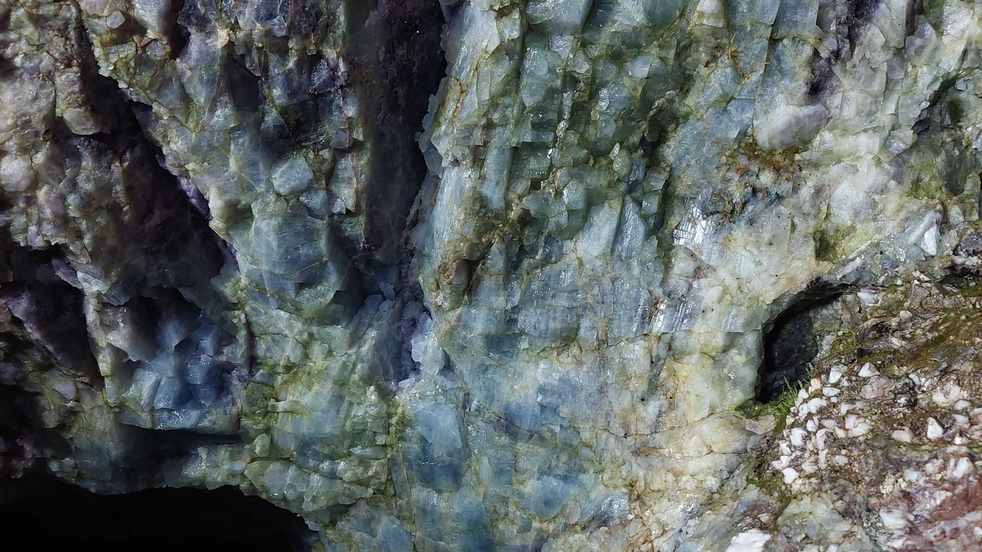 Close-up of rough mineral surface with blue-green crystal formations and natural rock textures.