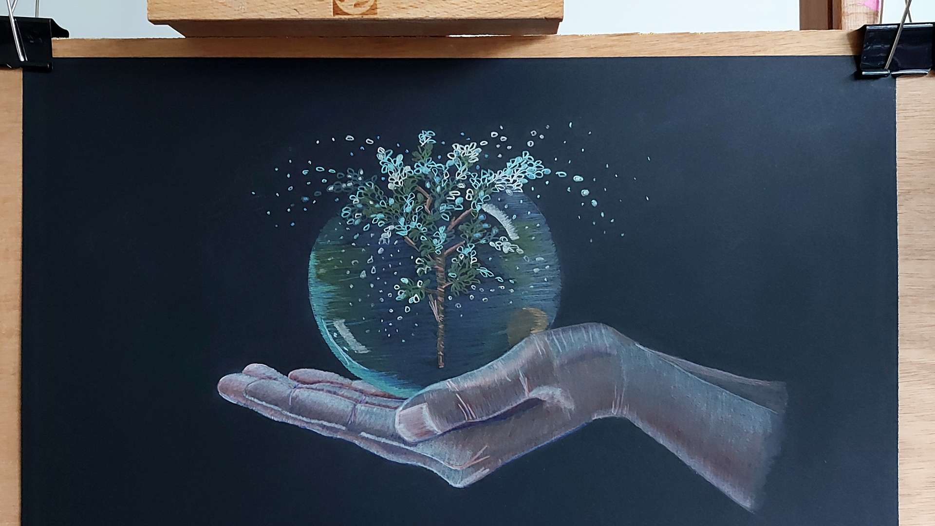   Artwork of a hand holding a glowing sphere with a tree inside, symbolizing nature and care, on a black background.
