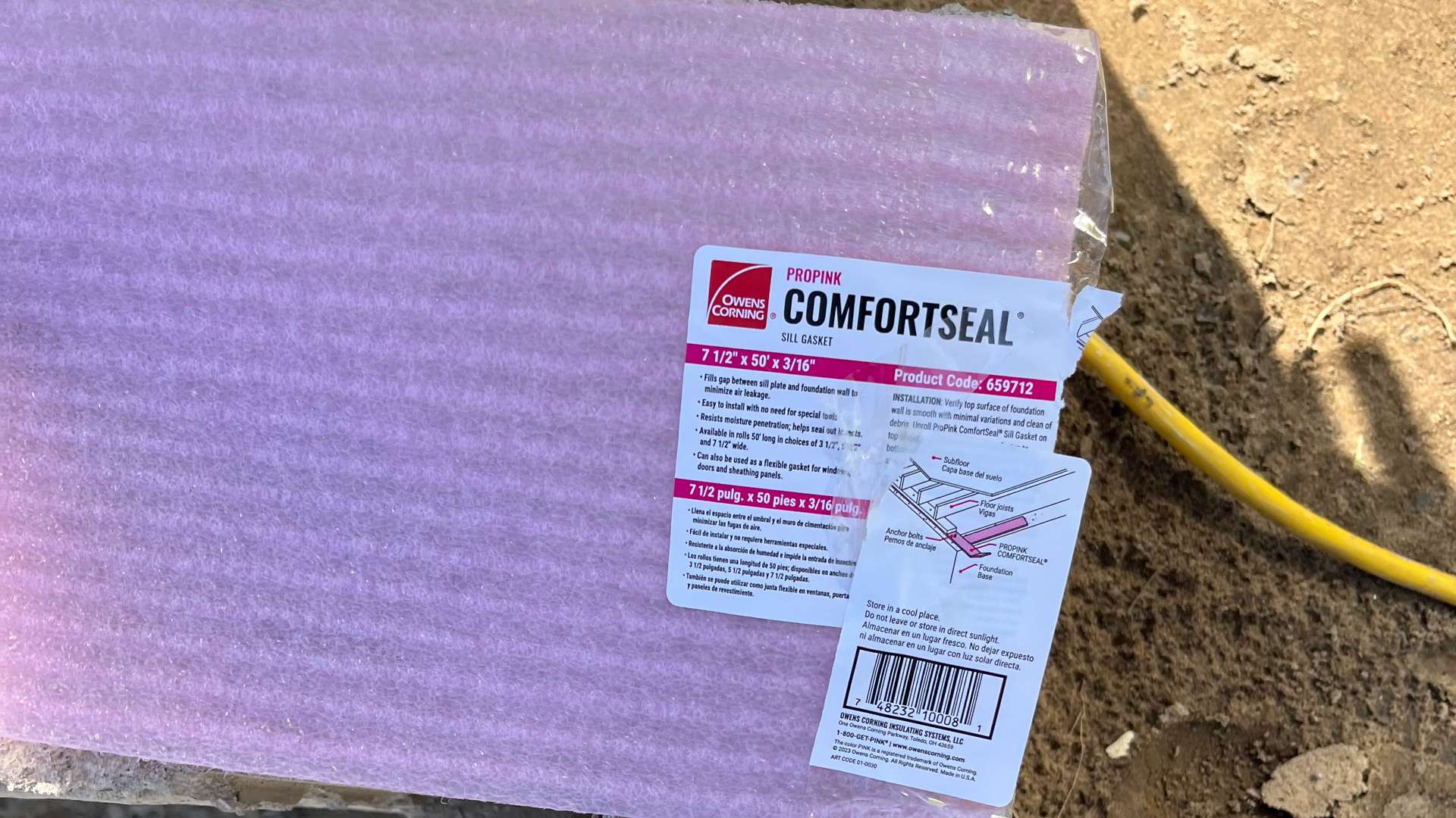 Owens Corning ComfortSeal insulation wrap in pink packaging placed on a concrete surface at a construction site.