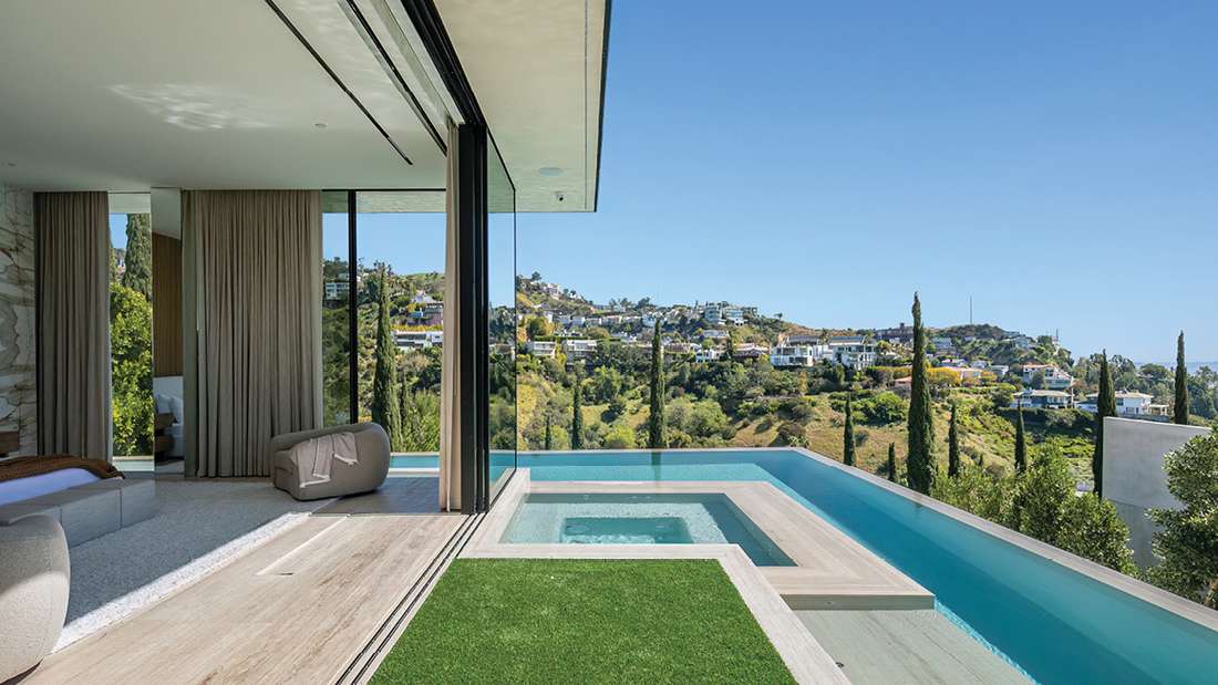 Luxury bedroom with seamless indoor-outdoor design, private infinity pool and spa, floor-to-ceiling glass walls, and panoramic hillside views.