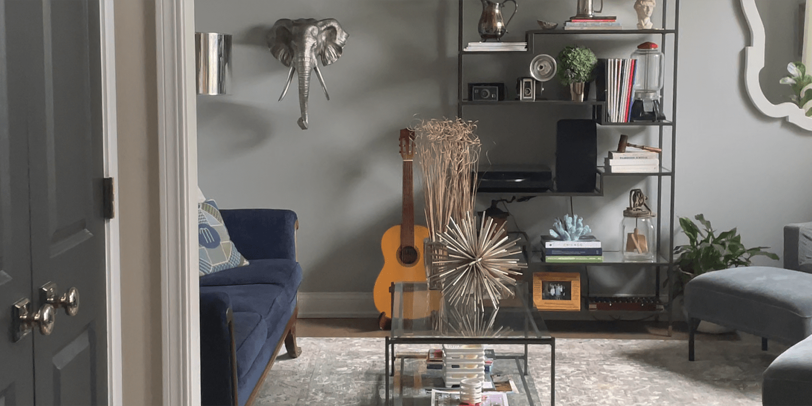 A livingroom with couches, an acoustic guitar, and decorative art on the wall.