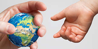 to menneskehender, en voksenhånd og en barnehånd, den voksne holder en miniatyrglobus