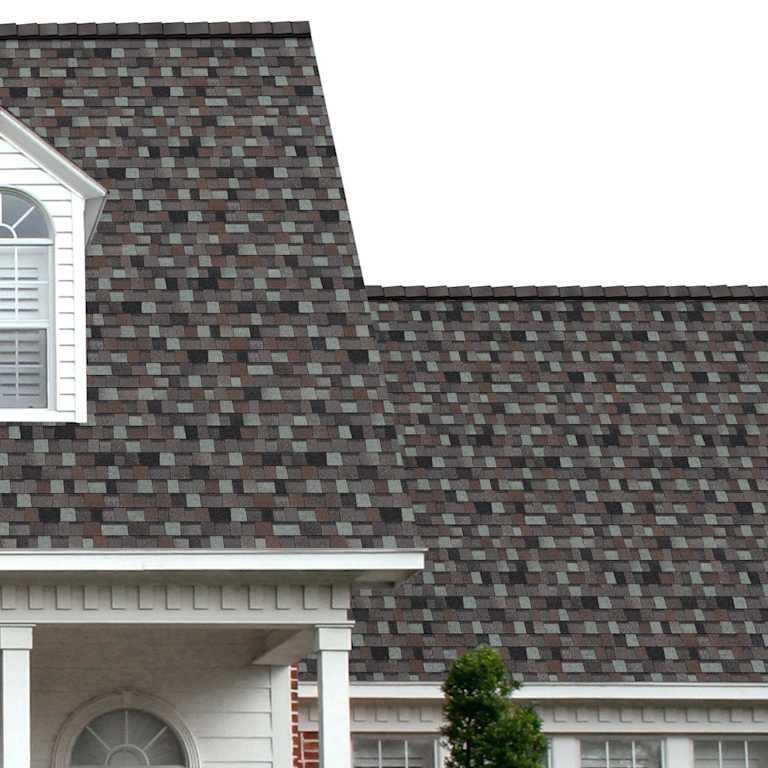 The porch entryway to a home depicts how well Storm Cloud TruDefinition® Duration® Designer® dark gray, light gray, green, and black shingles pair with the white horizontal paneling and a woodgrain door with white columns.