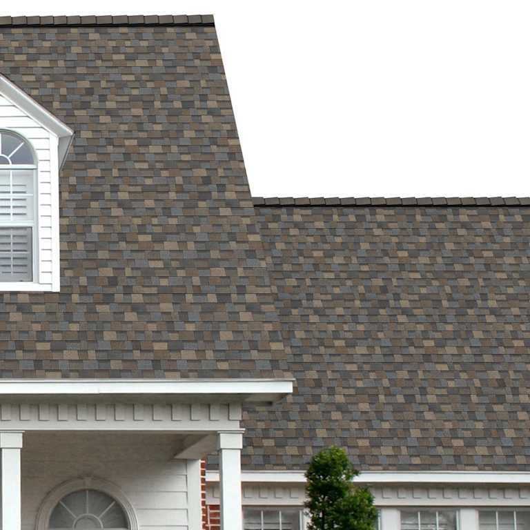 The porch entryway to a home depicts how well Black Sable TruDefinition Duration Designer brown, taupe, dark gray and black shingles pair with the white horizontal paneling and a woodgrain door with white columns.