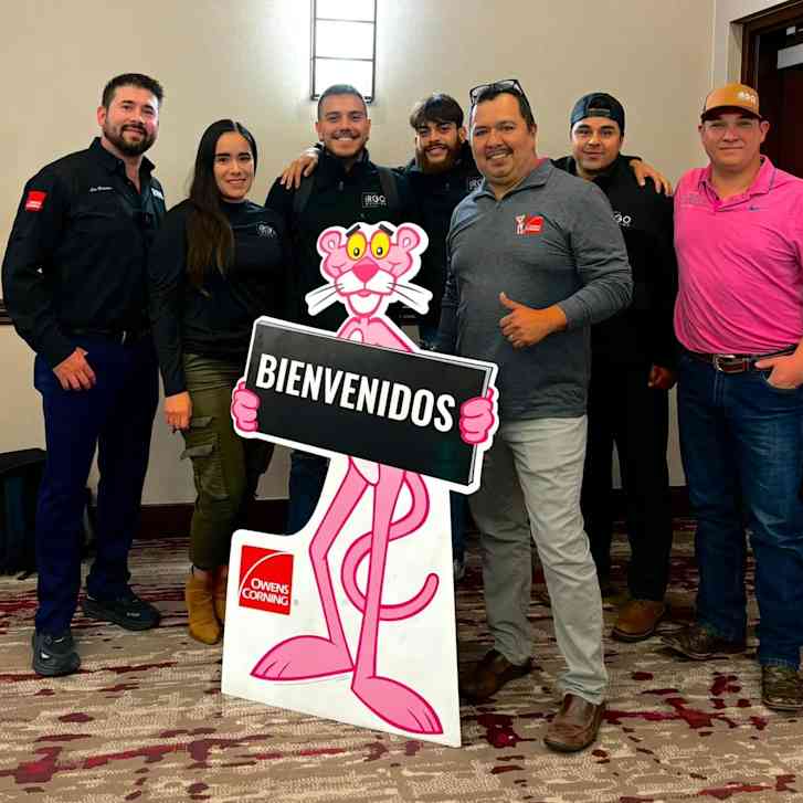 A group of contractors around a standing cutout of the Pink Panther holding a sign that reads "Bienvenidos"