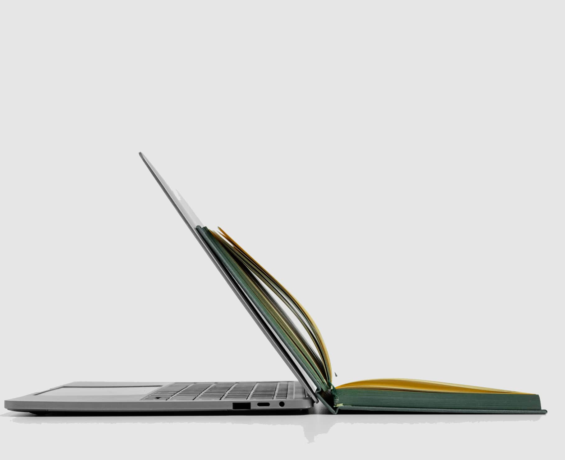 Laptop z otwartą książką ułożoną tak, że przypomina ekran komputera. 