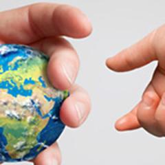 En voksen hånd strekker ut en globus til en barnehånd