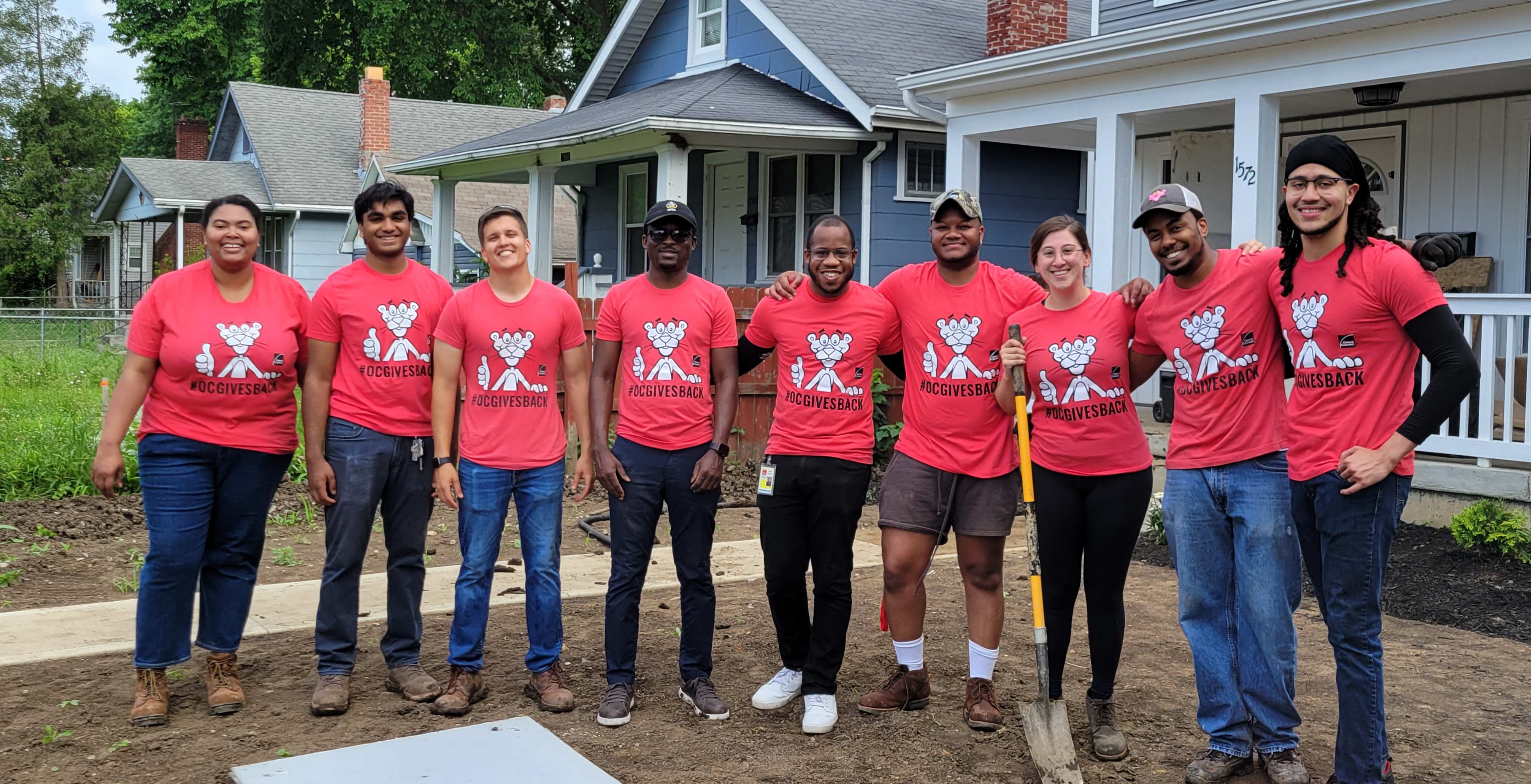Volunteers from Owens Corning gather around the new home owner from a completed Habitat for Humanity build