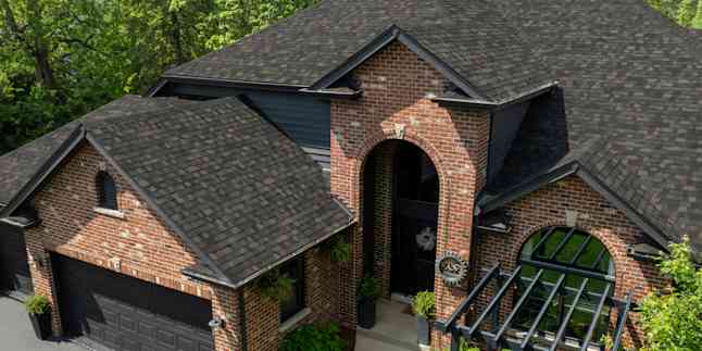Aerial view of a red brick home with arched entry and a new roof with Owens Corning TruDefinition Duration Black Sable asphalt shingles