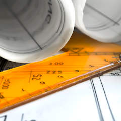 Drawings are scattered around along with a ruler and a pencil. 