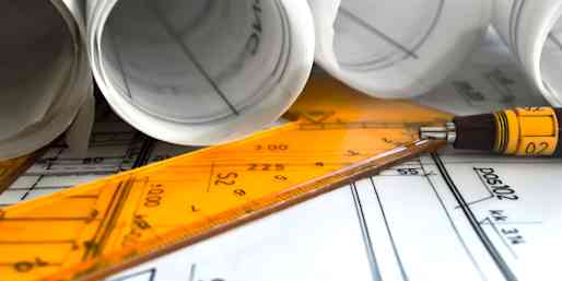 Ritningar ligger utspridda tillsammans med en linjal och en penna. 