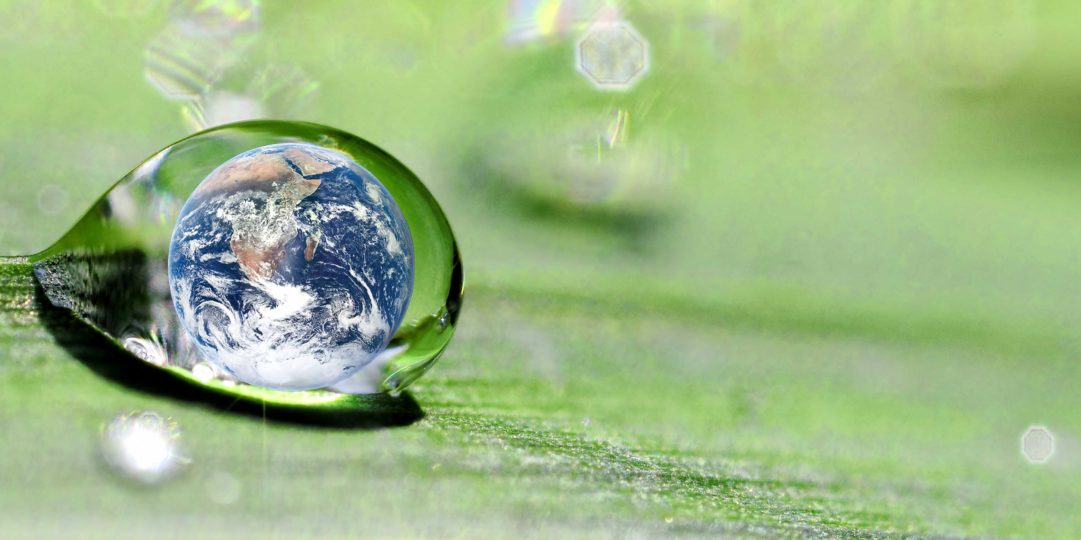 En globus er inne i en dråpe vann som renner av et grønt blad.