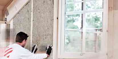 En man isolerar väggen på vinden