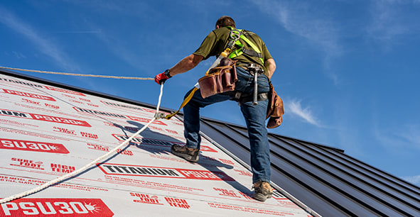 Contractor walking on a brown metal roof cladding installing on Titanium PSU30 underlayment