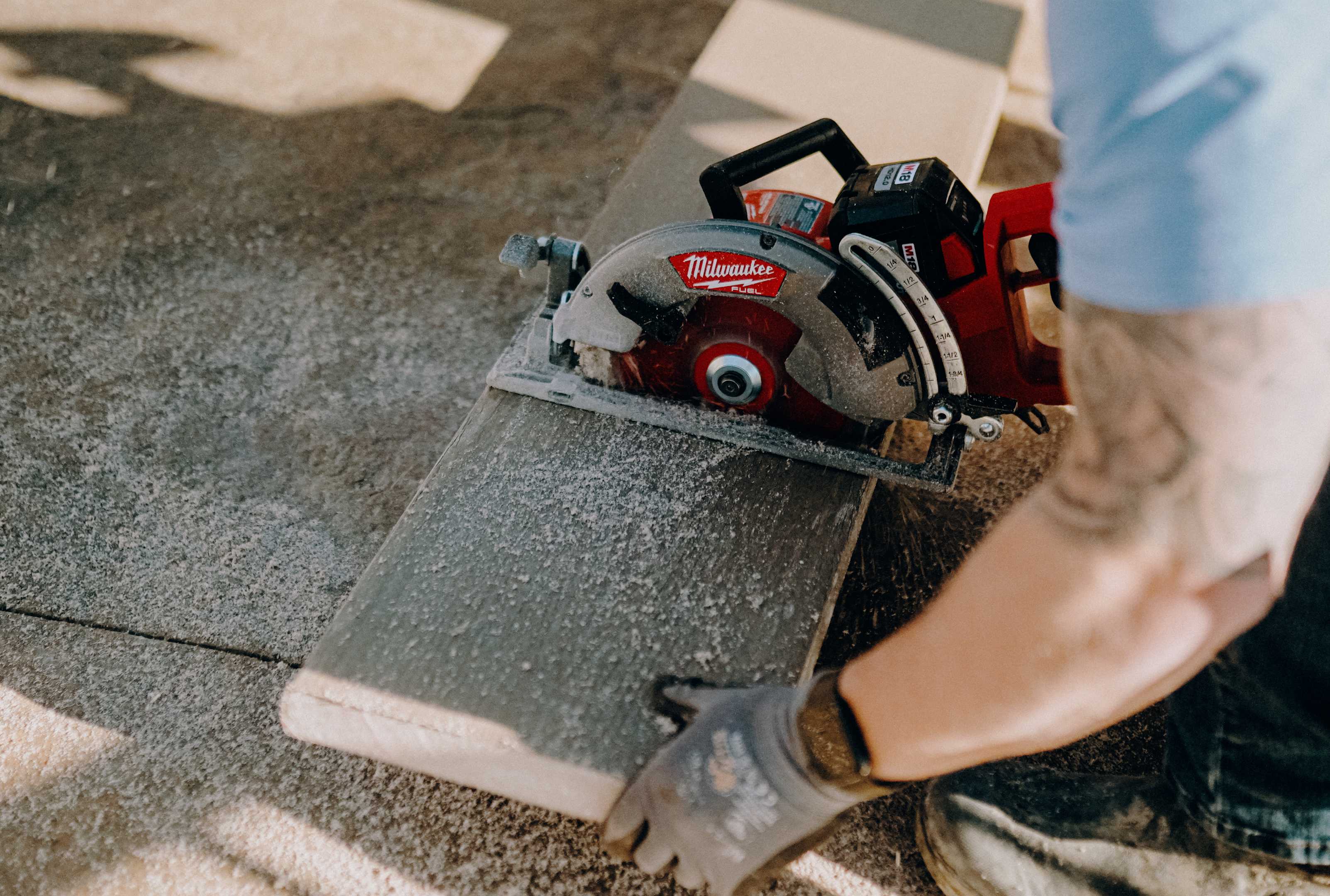 Circular saw cutting through a composite decking board as sawdust scatters across the work surface.