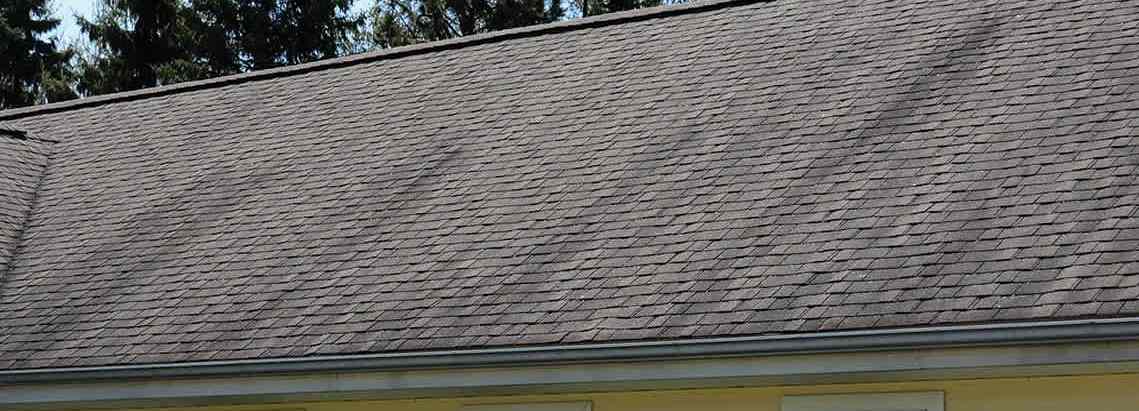 Brown asphalt shingles with dark algae streaks.
