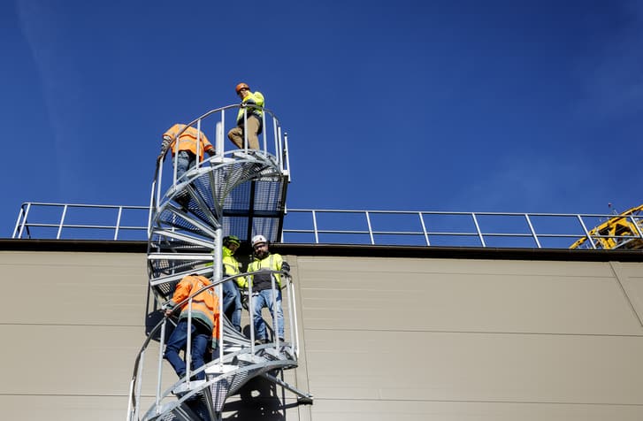 The partners Paroc and Peab is walking down the stairs of a building on site. 