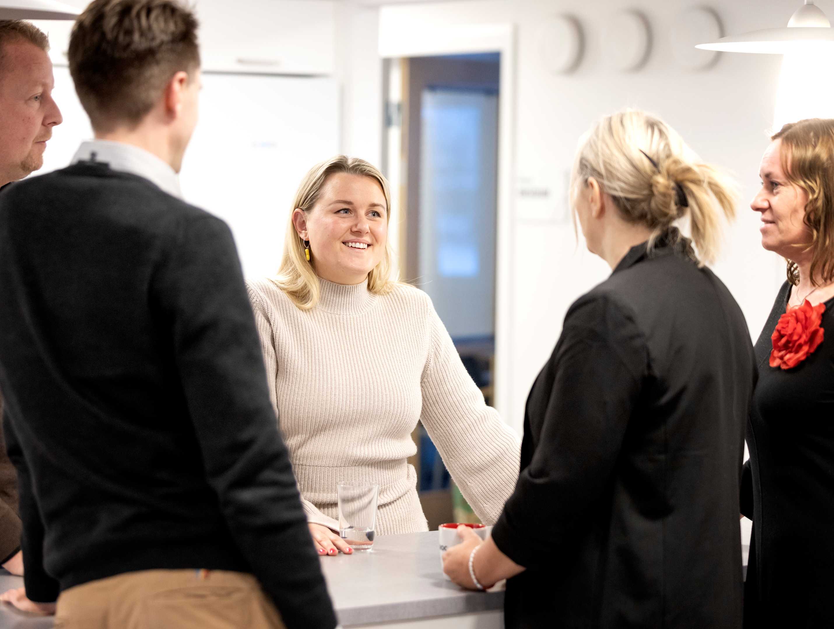 Flere kolleger fra Paroc står rundt om et bord i et kontormiljø og snakker.