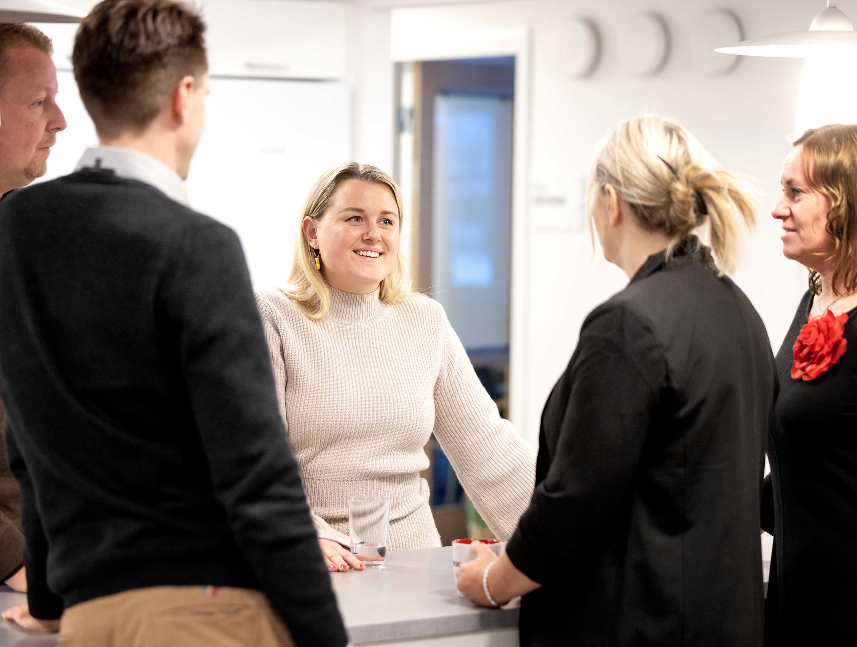 Flera kollegor från Paroc står kring ett bord i kontorsmiljö och samtalar. 