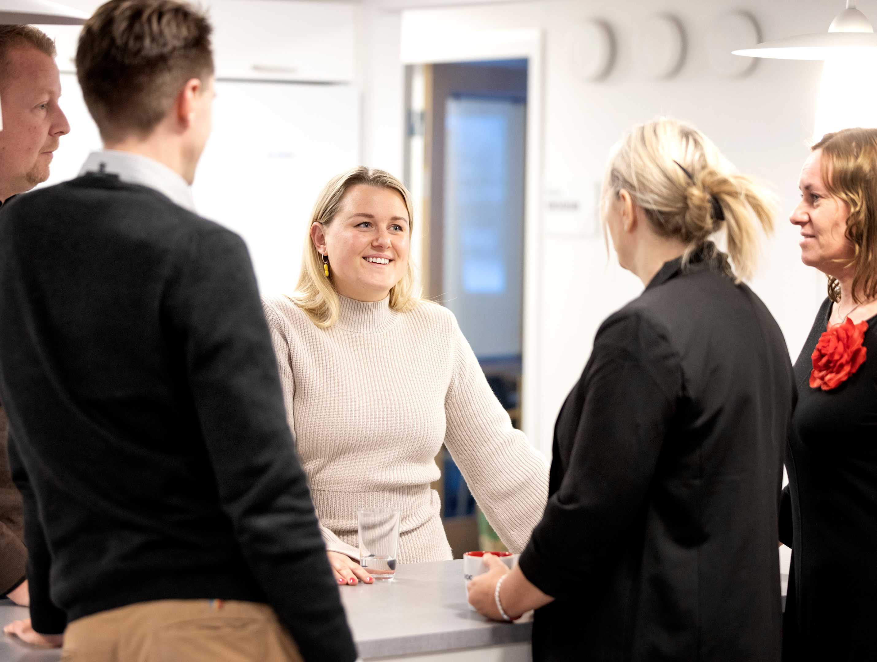 Flere kolleger fra Paroc står rundt et bord i et kontormiljø og prater.