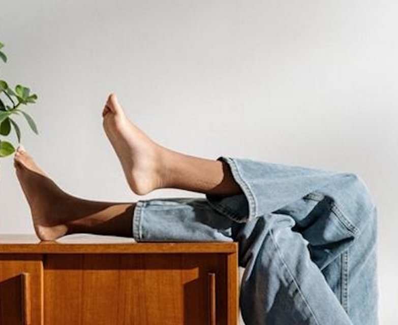 Female legs with jeans propped up on shelf.