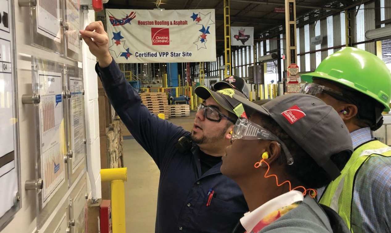 A group of employees discuss projects while looking at the screen of a laptop.