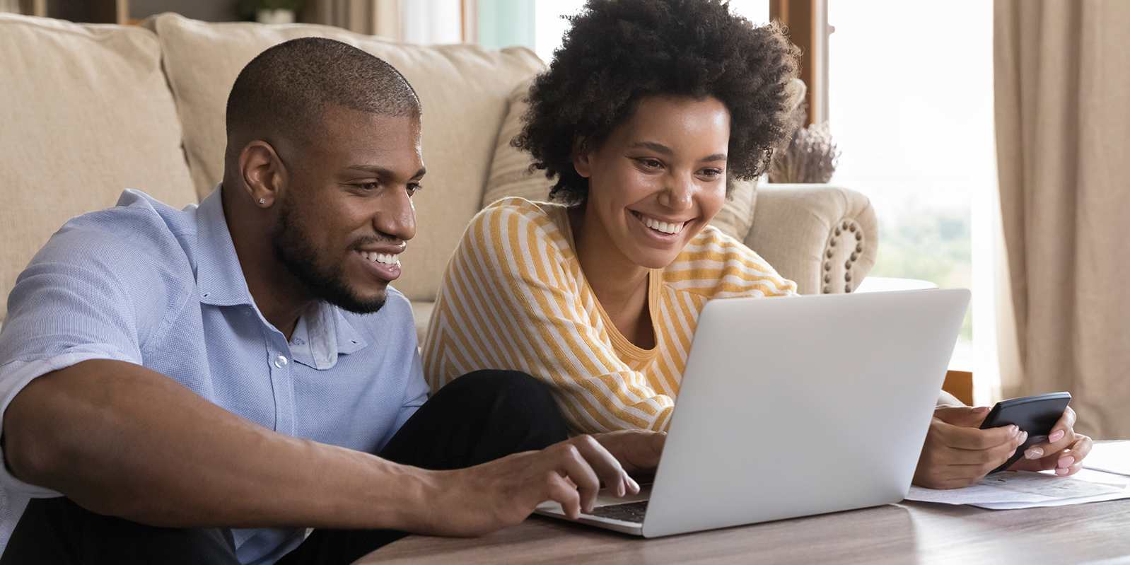 Man and woman sitting on a couch using a latpop