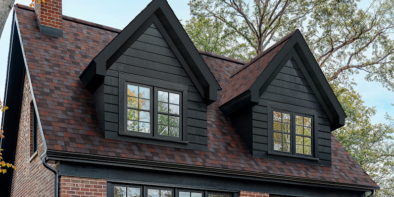 Duration Designer shingles in Merlot color installed on a red brick home with black trim and accents.