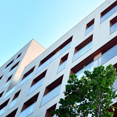 A white building with ventilated facade is seen from beneath with a light blue sky in the background.