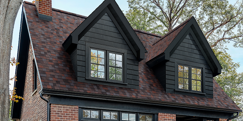 Duration Designer shingles in Merlot color installed on a red brick home with black trim and accents.