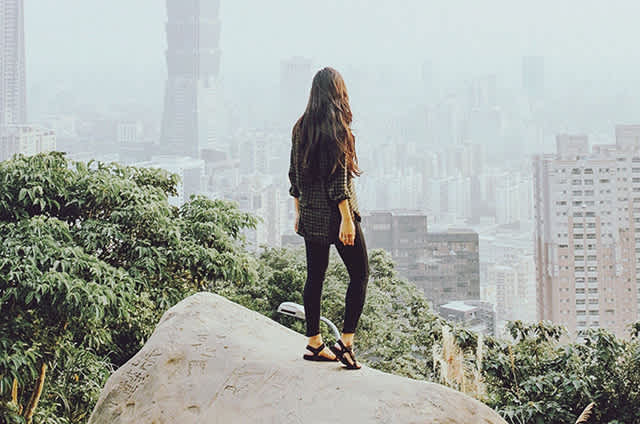 Kvinna på sten med utsikt över staden från en hög punkt