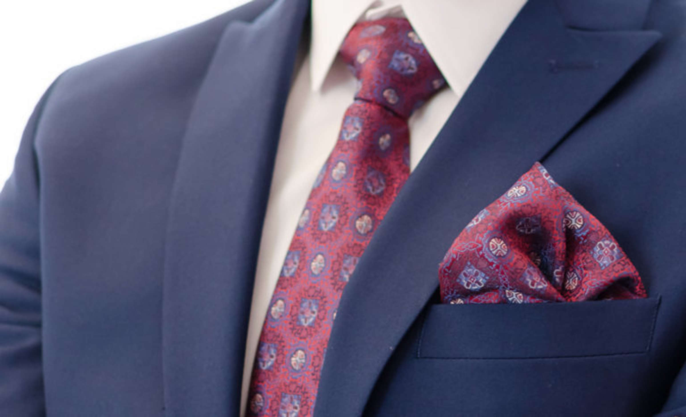 Top portion of a blue suit jacket with burgundy patterned tie