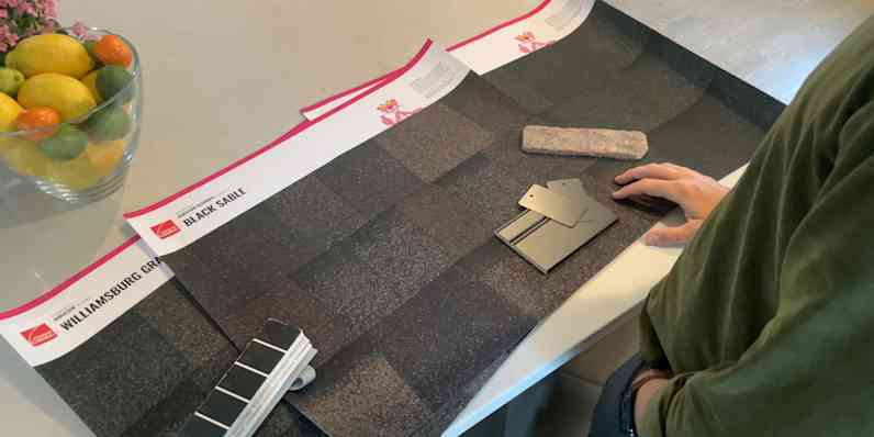 Homeowners looking at Shingle Color Posters in front of their home.