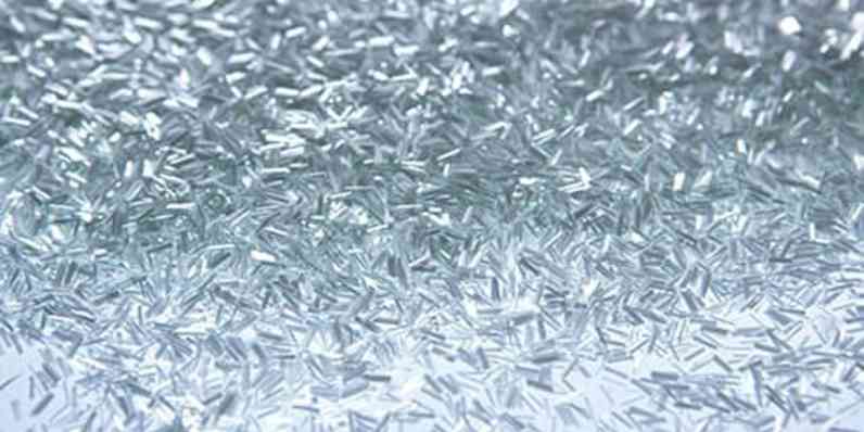 Close-up of loose, shiny chopped fibers scattered across a reflective surface.