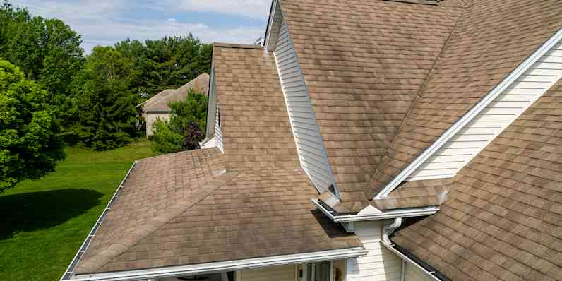 Medium tan rooftop with dark coloration on the shingles. 